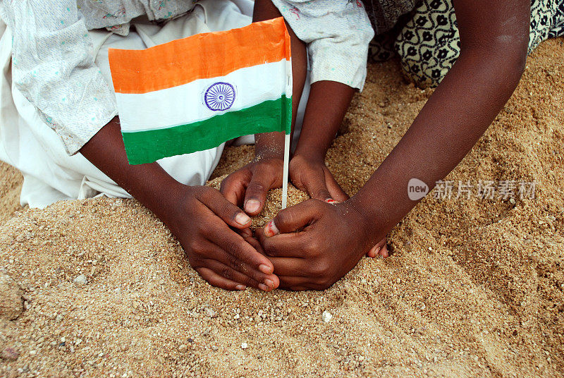 一双小手在沙地上插着一面微型的印度国旗