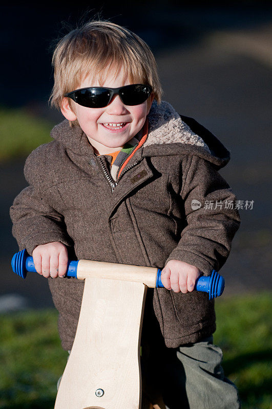 小男孩骑着滑板车微笑着