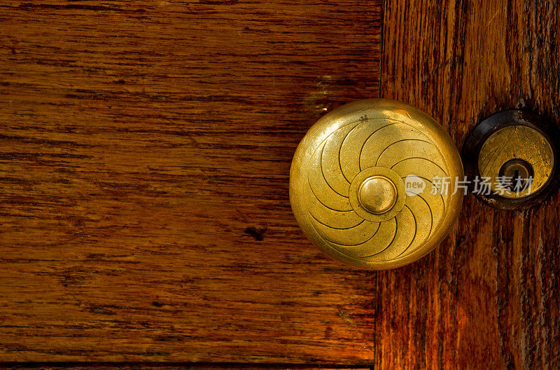 古董黄铜门把手和钥匙锁在旧橡木门上。