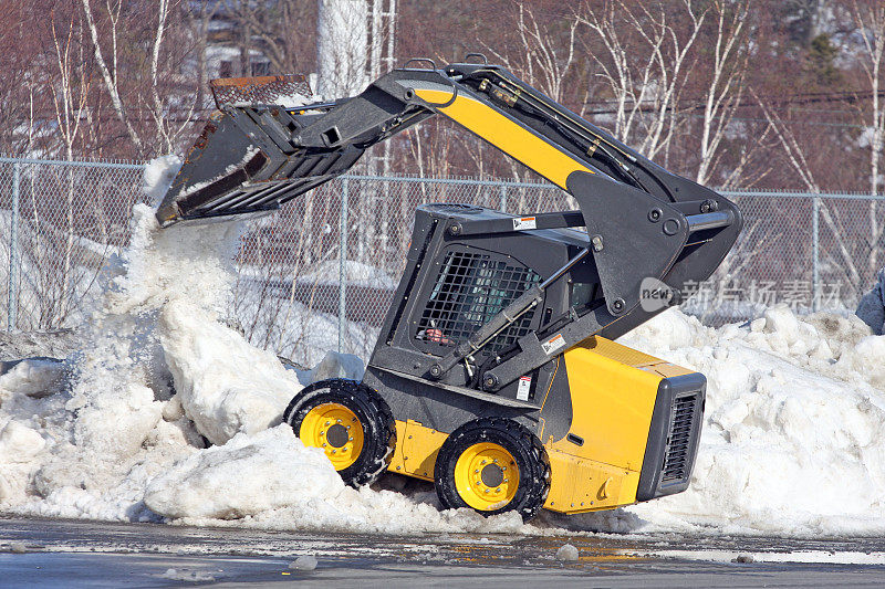 迷你前端装载机在一个停车场清除雪