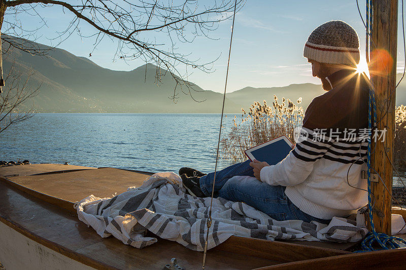 一个年轻人在湖边拿着平板电脑休息