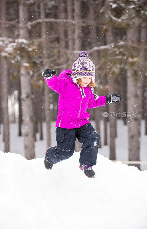 女孩在冬天从雪堆上跳下来