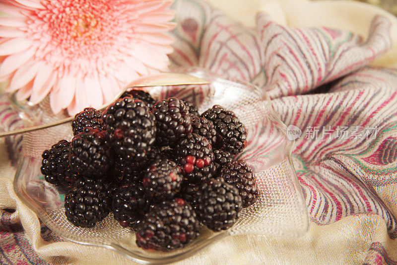新鲜的黑莓水果在一个碗与花。