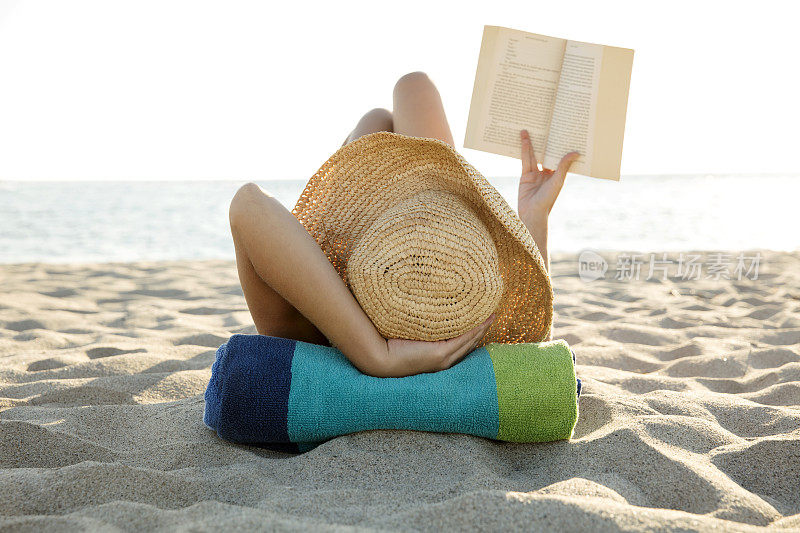 一个女人躺在沙滩上看书