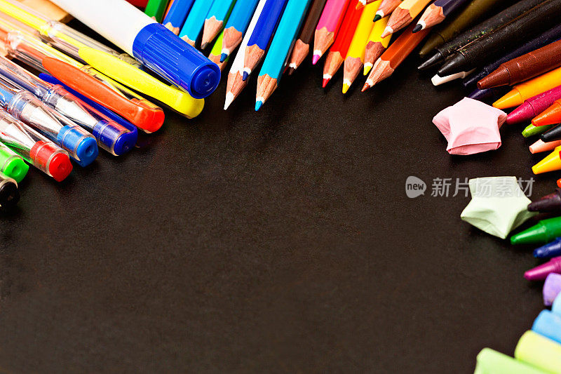 彩色钢笔、铅笔和彩色粉笔环绕着黑色的拷贝空间