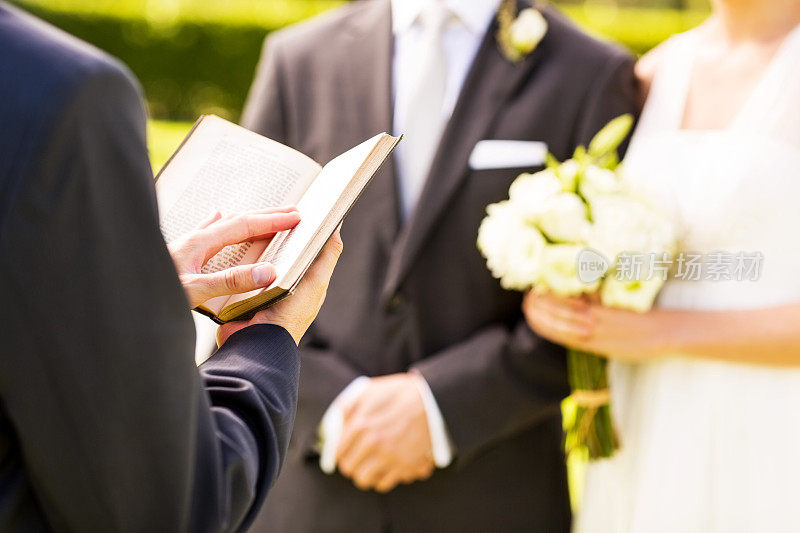 牧师和新郎新娘在户外婚礼上拿着圣经