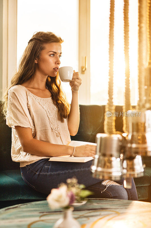 年轻女子在咖啡馆里喝着咖啡放松。