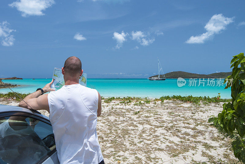 男人在车旁看地图，海滩