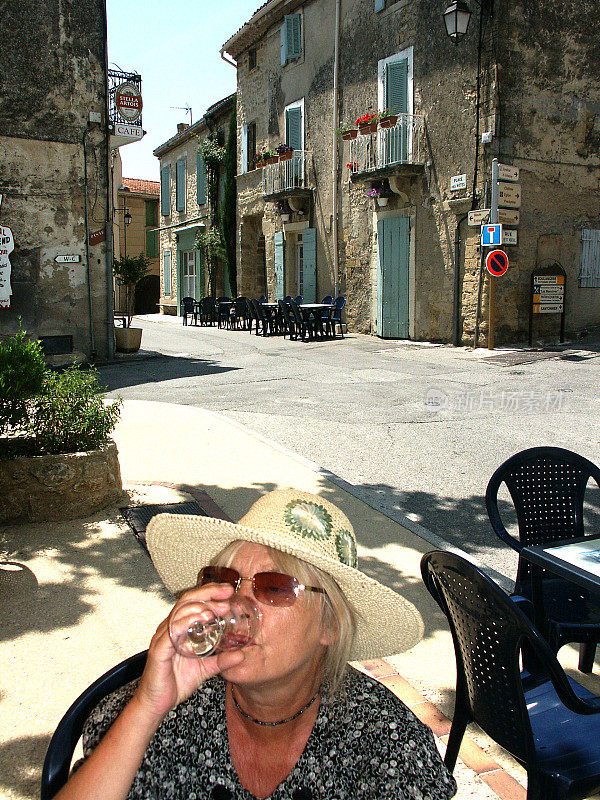 老妇人在阳光明媚的法国街角喝酒