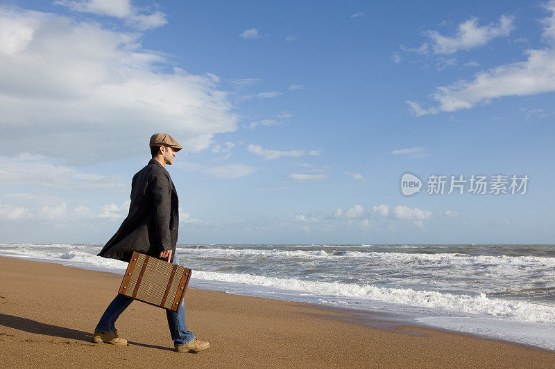 在海滩上拄着旅行箱走路的人