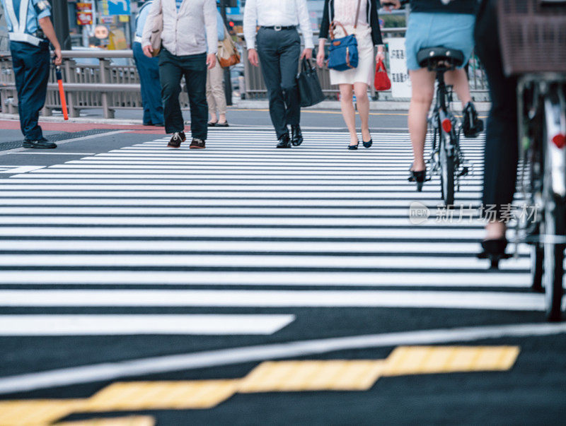 在日本东京，人们和骑自行车的人过马路
