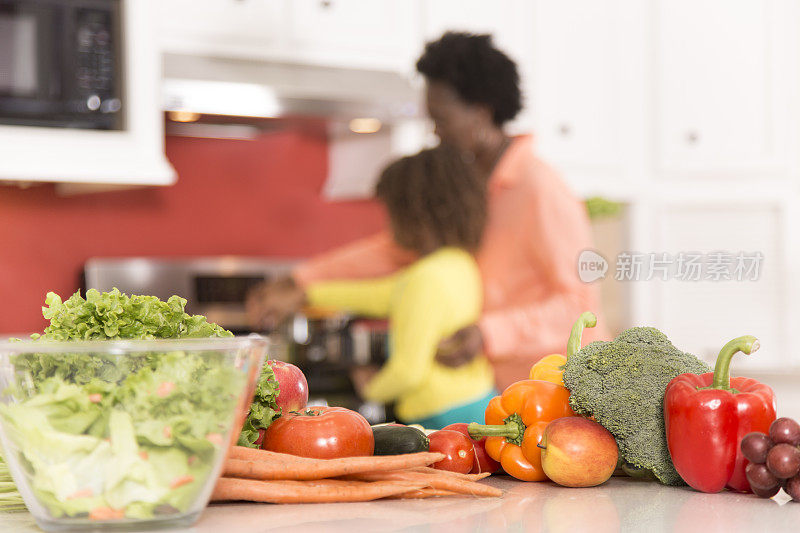 祖母或母亲和女儿一起在家里厨房做饭。