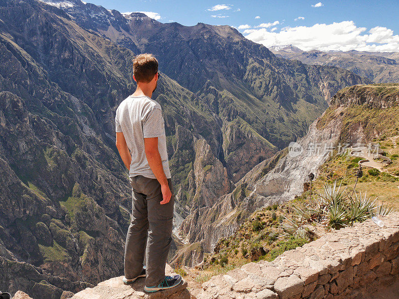 一个年轻人站在秘鲁科尔卡峡谷的一个深深的大峡谷上