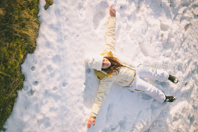 一个女人带着狗在雪地里走在村里的街道上