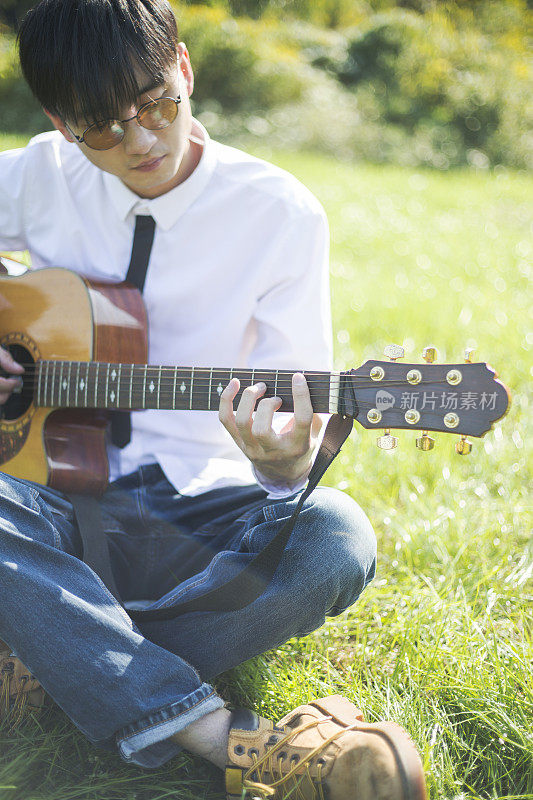 一个年轻人在草坪上弹原声吉他