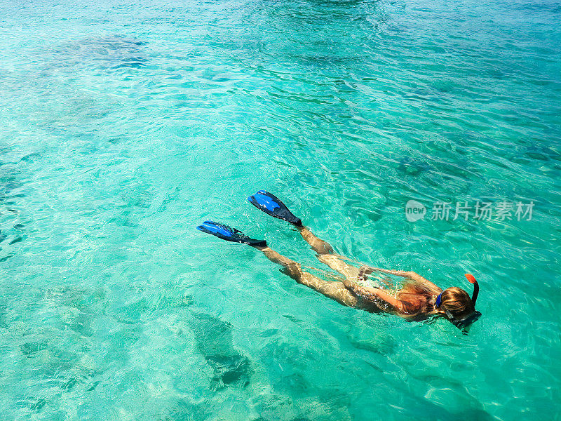 一位女性浮潜在蓝色的水中