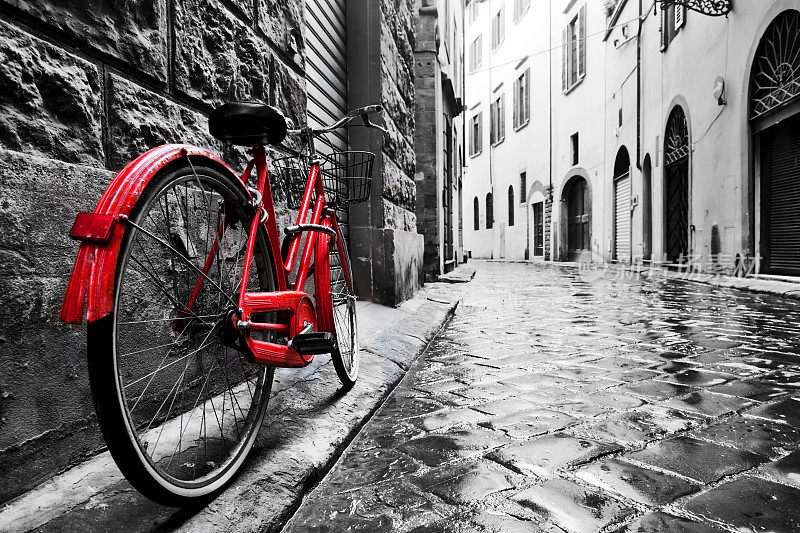复古的红色自行车在老城的鹅卵石街道上。颜色在黑色和白色