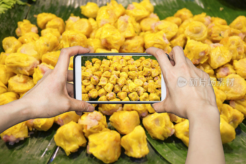 一个女孩在用手机拍香蕉叶蒸饺