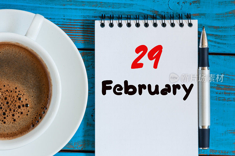 2月29日。月29日，日历在记事本上的木制背景上靠近早晨的杯子和咖啡。冬天的时间。文本空白