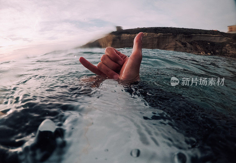 冲浪者在海里展示shaka标志(POV)