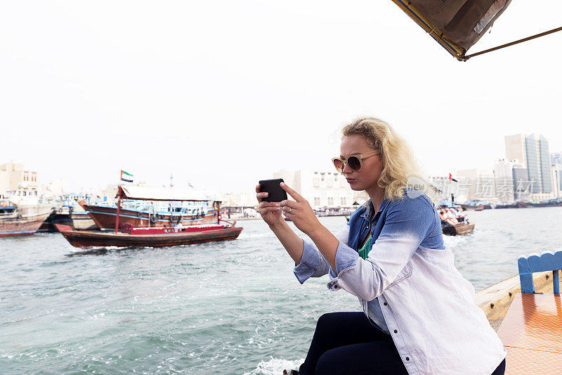年轻女性游客享受老迪拜访问使用传统船，阿布拉