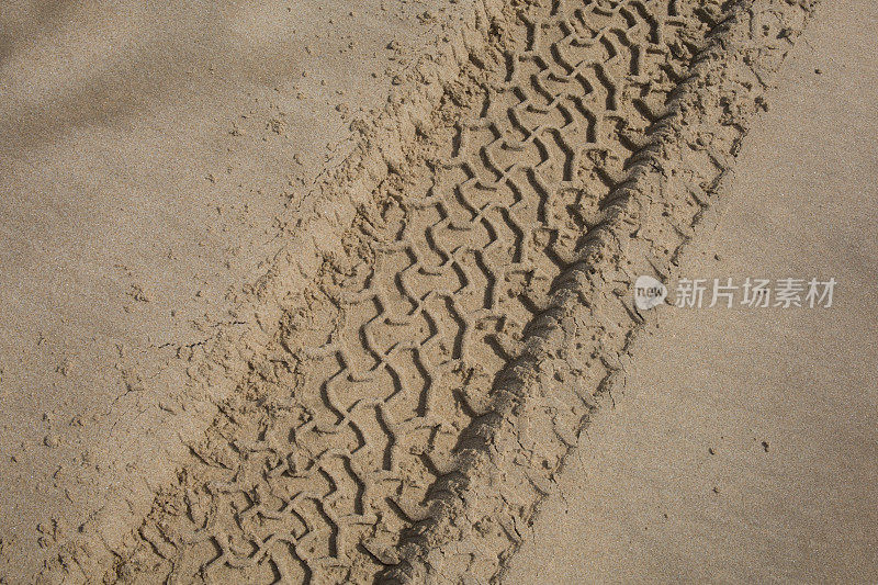 沙地上有轮胎印。沙地上车轮的痕迹