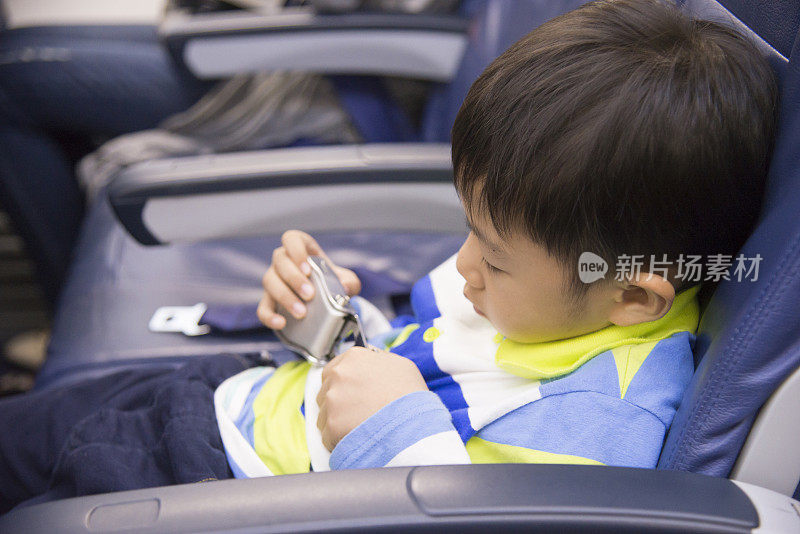 6岁亚洲男孩在飞机上系好安全带。带孩子的安全旅行理念