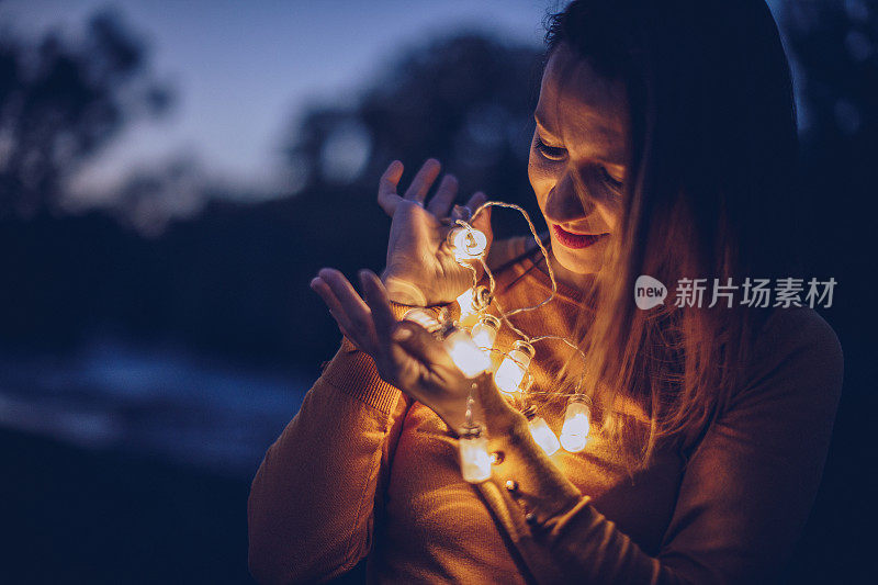 微笑的女人站在户外，带着灯