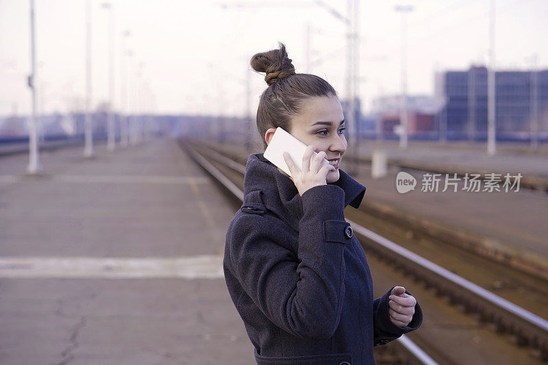 一个年轻女子在火车站用智能手机