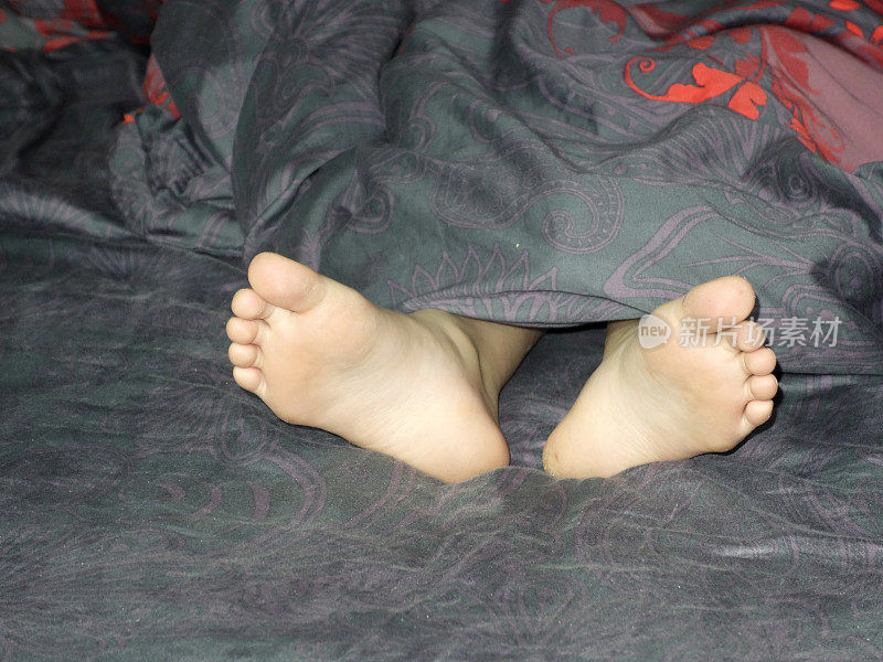一个小女孩光着脚躺在彩色的床上