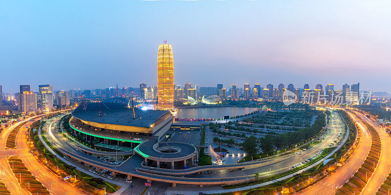 环形道路被湖边的摩天大楼包围，夕阳下的城市天际线。郑州,中国