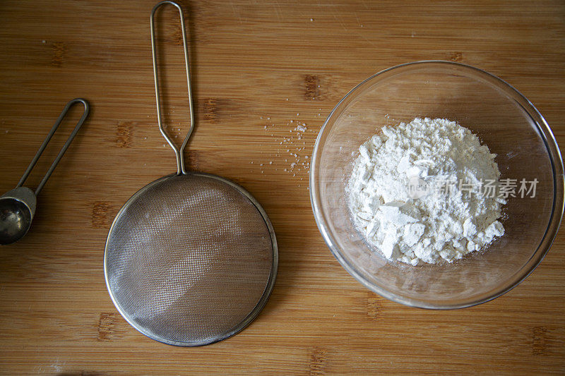 面粉粉和筛子放在木桌上，准备做自制蛋糕