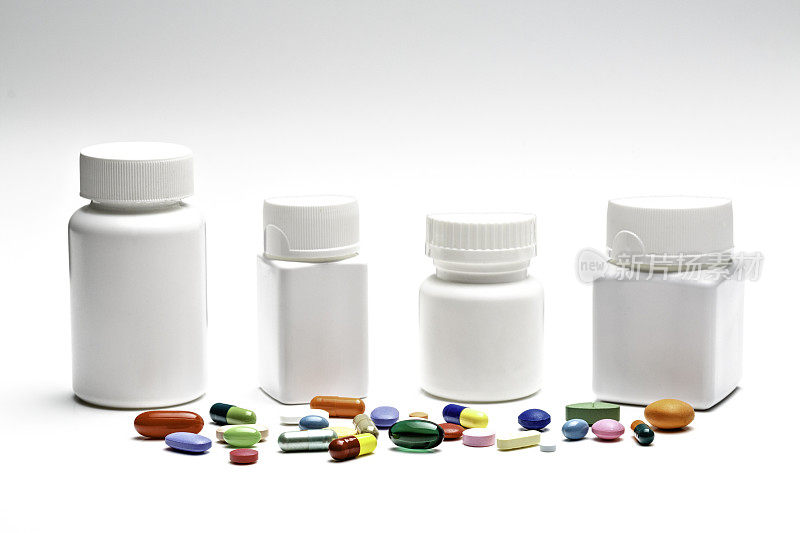 一组不同形状的白色塑料瓶，药丸和胶囊在白色背景