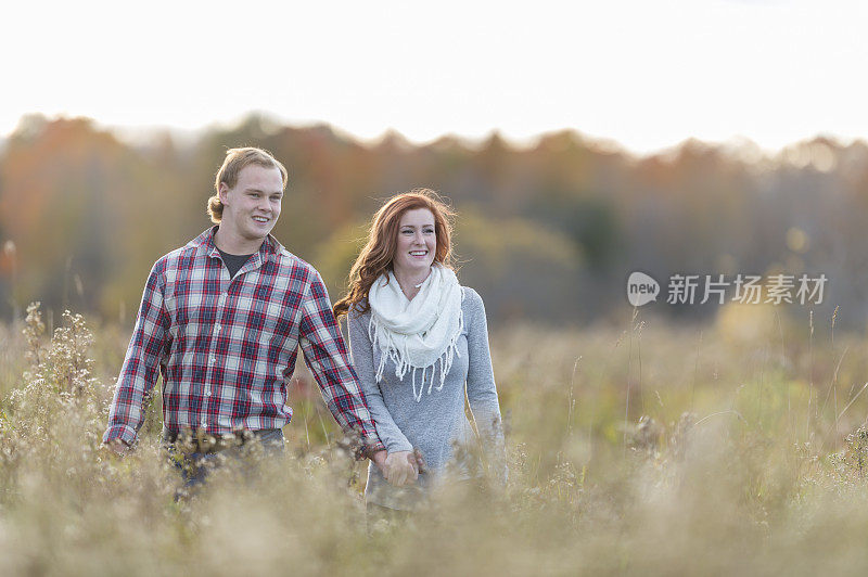 一对情侣在秋天的草地上散步