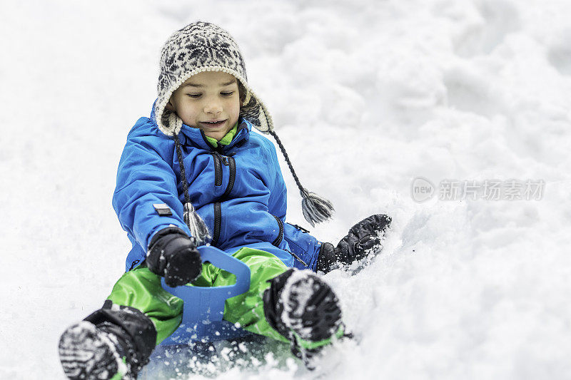 男孩在雪地上用雪橇滑行