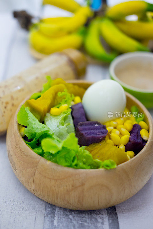 新鲜水果和蔬菜沙拉(生菜，南瓜，玉米，山药和煮鸡蛋)与奶油沙拉在木碗。健康食品的概念