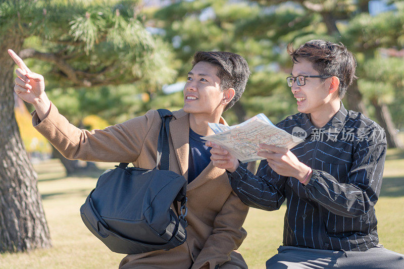 年轻的亚洲男子和日本朋友寻找旅游地点使用手机和花时间在亚洲旅行