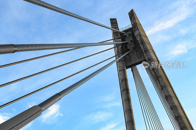 悬索桥的缆柱以蓝天和白云为背景。