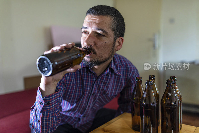 年轻悲伤的醉酒男子喝啤酒和酒精感到浪费，孤独和绝望的痛苦和情绪压力。人与酗酒、上瘾和男人抑郁的概念。