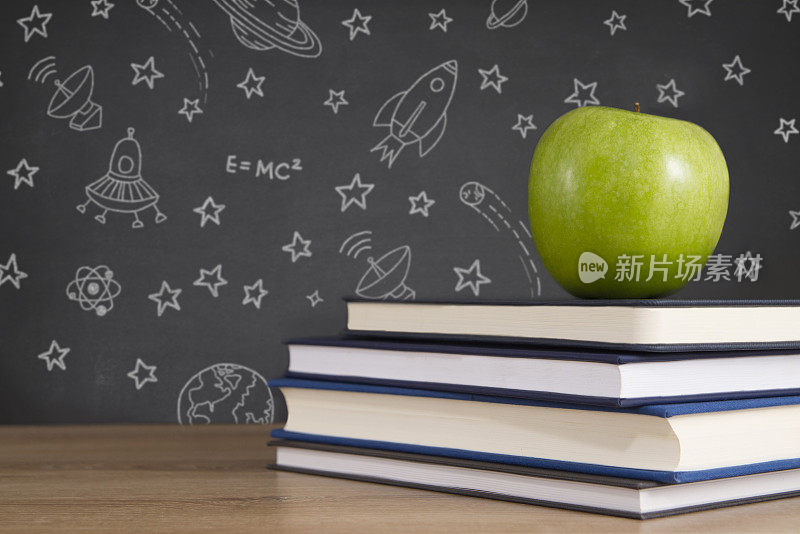 绿色苹果在木制课桌和黑板上