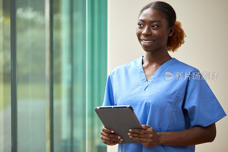 微笑的女护士或医生的肖像穿着擦洗与数字平板电脑