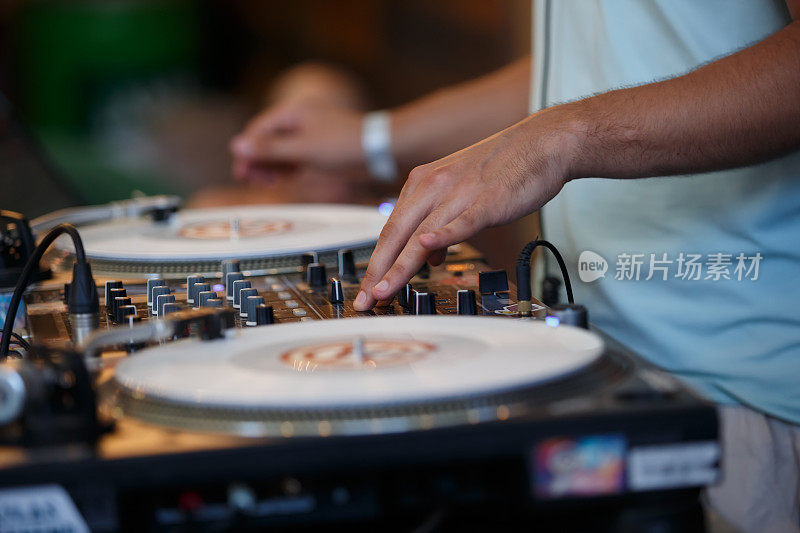 俱乐部DJ用混音器和转盘刮黑胶唱片。专业音乐节目主持人在派对上表演