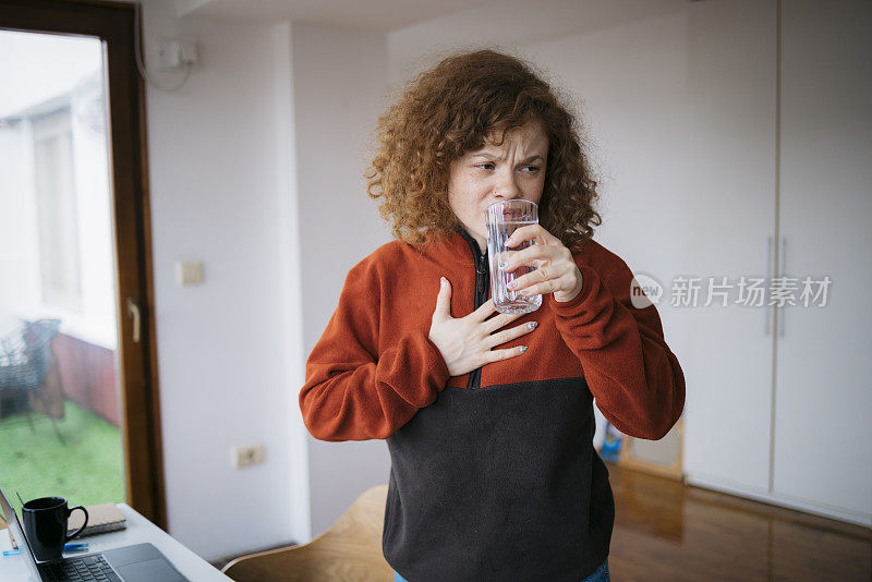 女人在家里喝一杯水，胸部疼痛