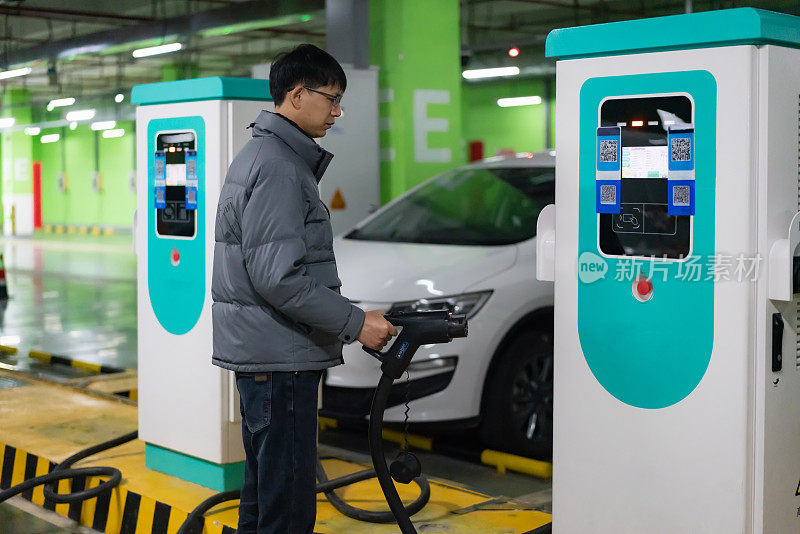 亚洲男子正准备给电动汽车充电