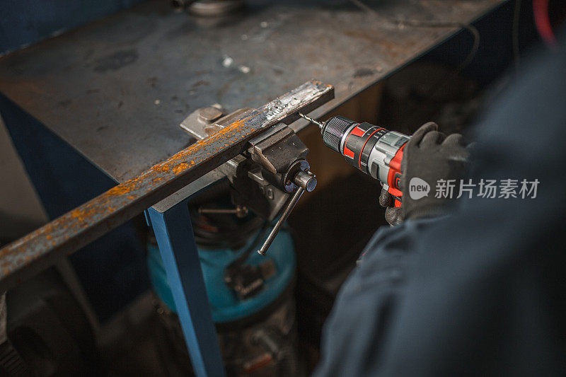 一个工人的手在金属车间用钻头钻金属管的特写