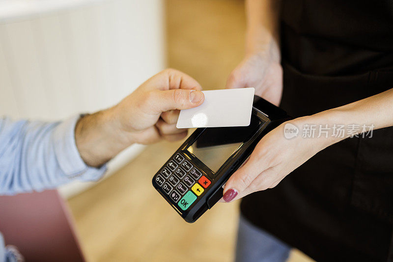 一名男子在餐厅用信用卡进行非接触式支付的特写