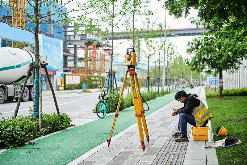 建筑工人在人行道上操作量具