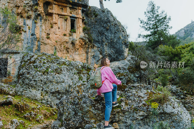 穿着粉色毛衣背着背包的女人在土耳其森林里探索古城遗址