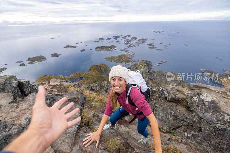 徒步旅行者帮助队友到达山顶