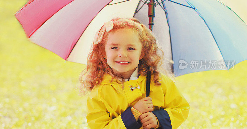 快乐的小女孩在阳光明媚的秋天公园里撑着五颜六色的伞